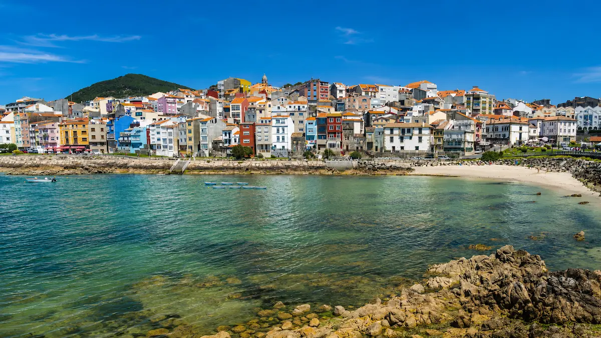 Vista de A Illa de Arousa con sus casas de colores, la ría, pequeñas embarcaciones y el monte al fondo.