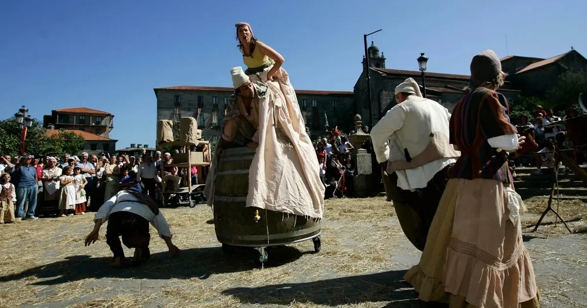 Actores caracterizados de época medieval representando una escena con barril en la Feira Franca de Pontevedra