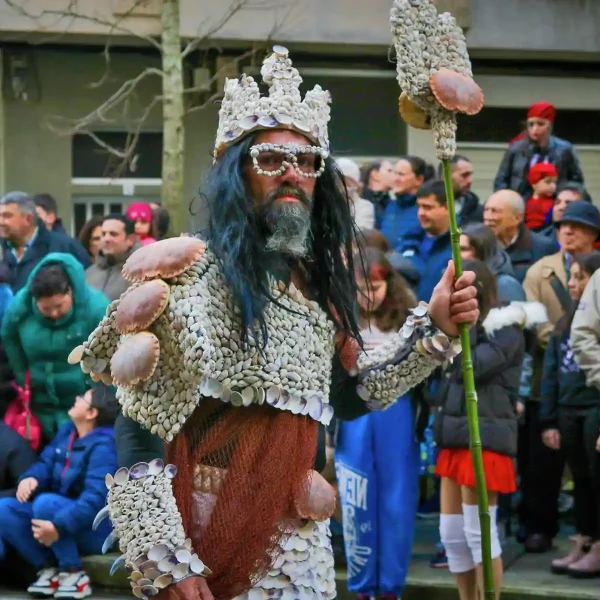 Persona disfrazada con traje de conchas marinas durante el Carnaval de Vilagarcía de Arousa, rodeado de espectadores.