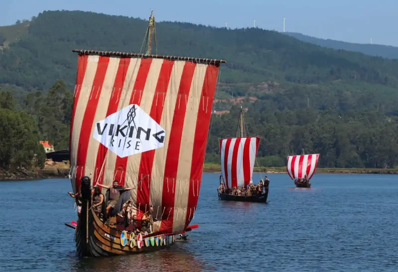 Barcos vikingos llegando a la costa durante la Romería Vikinga de Catoira, una de las Fiestas de Interés Turístico Internacional en Pontevedra.