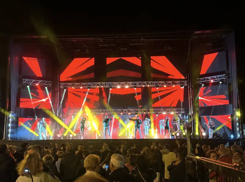 Escenario de la Orquesta Capitol durante una actuación en vivo, con un impresionante despliegue de luces y pantallas LED ante un público entregadas.